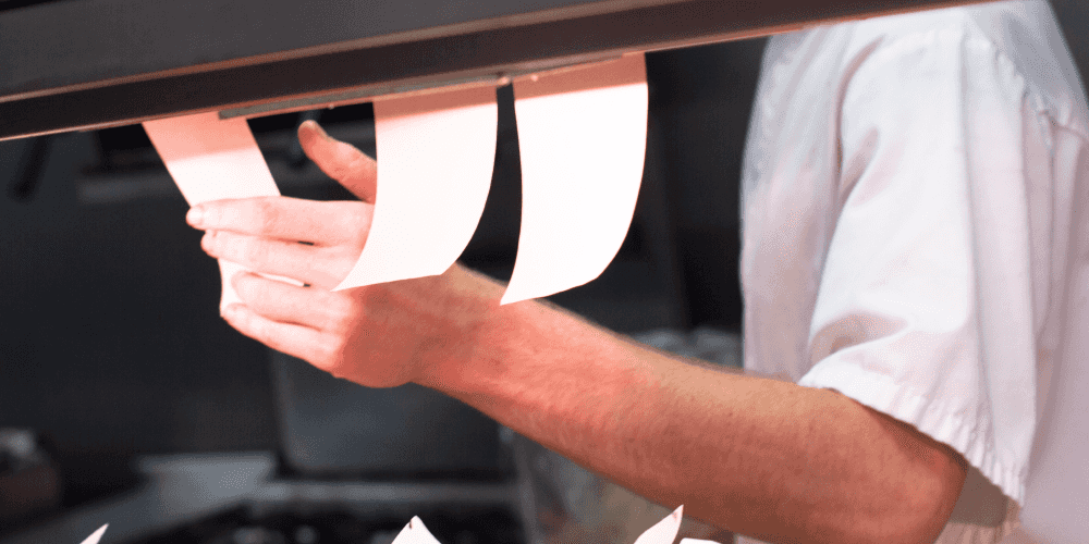 Сотрудник на кухне смотрит чек, распечатанный на чековом принтере, с помощью системы автоматизации ресторанного бизнеса Restik
